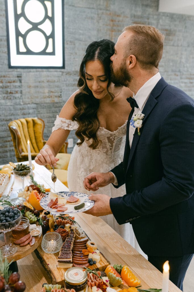 Photo of bride and groom eating from a grazing tablescape created and styled by Marcuterie of Kitchener-Waterloo and Elmira for their wedding